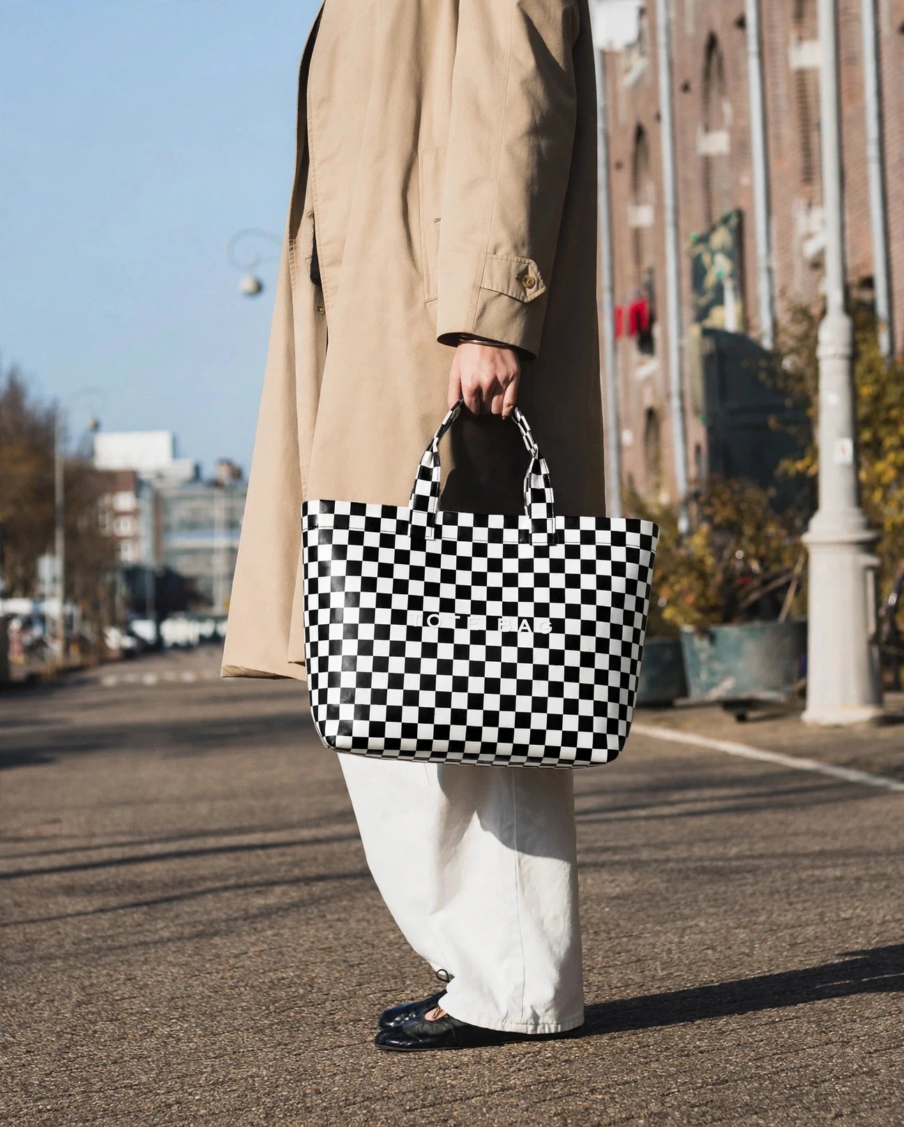 Black Checkers tote carried by hand on a city street