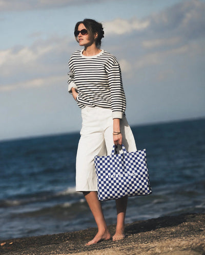 Blue Checkers tote carried by hand at the shoreline